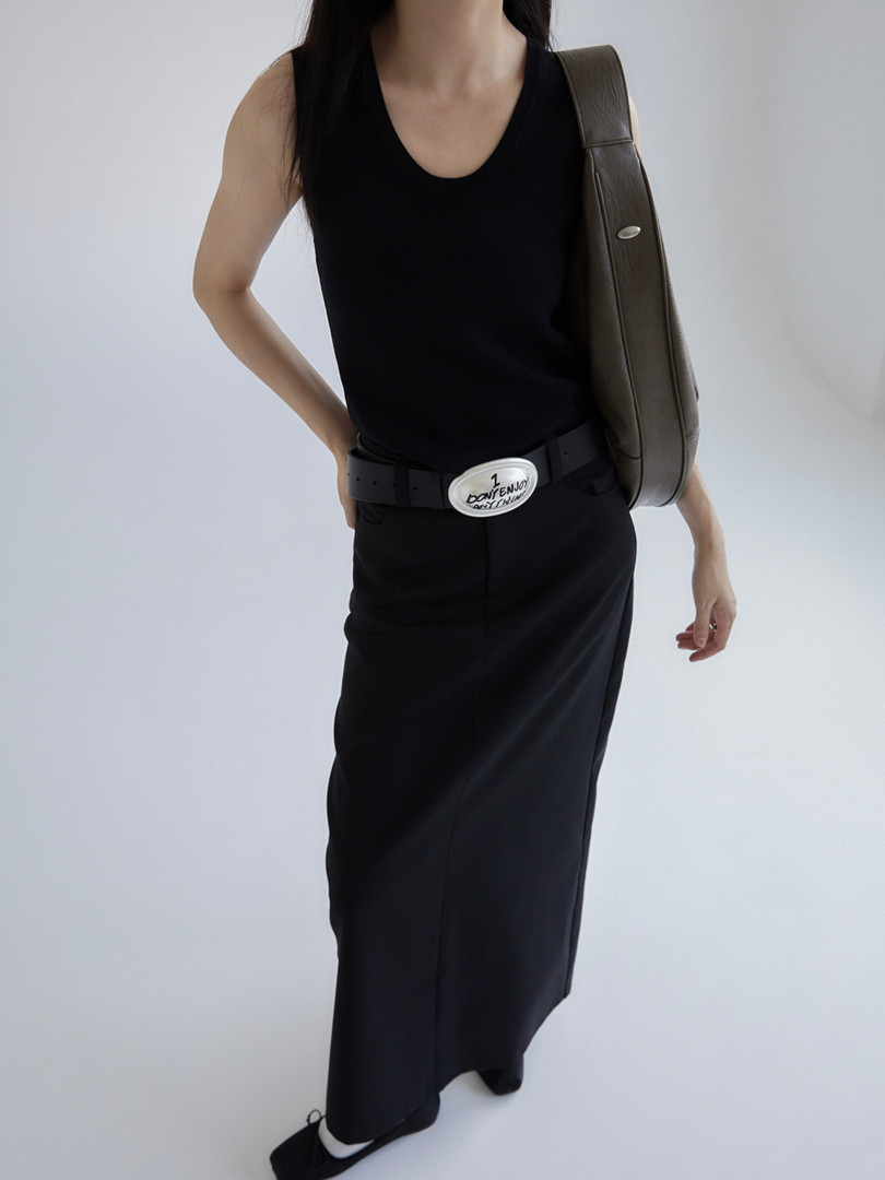 Woman wearing a black sleeveless dress with a belt and shoulder bag