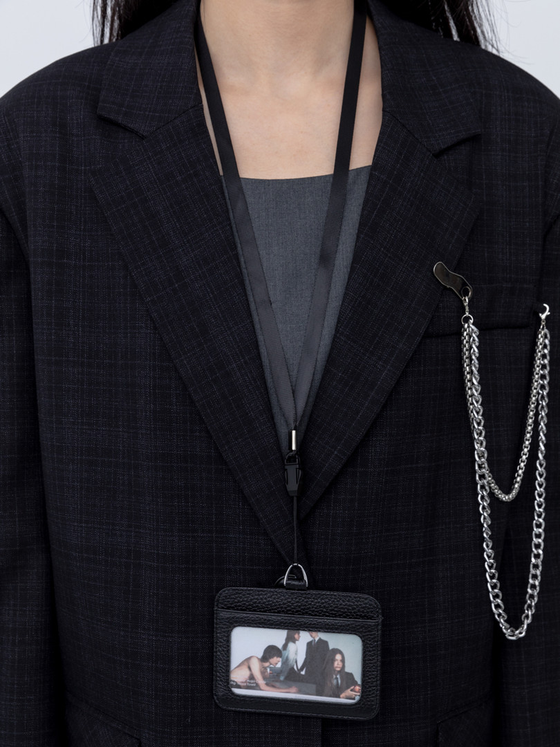 Black blazer worn by a model with a chain accessory and lanyard pouch