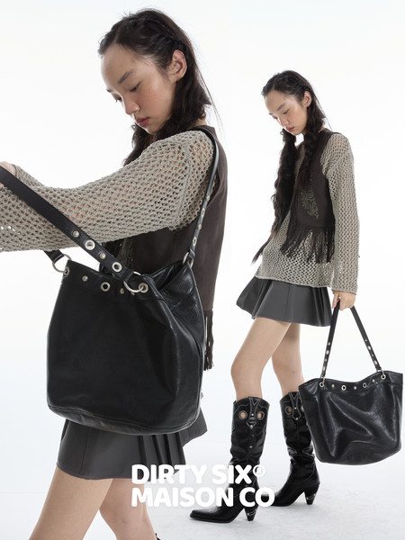 Black leather shoulder tote bag worn by a model in a fashion editorial image