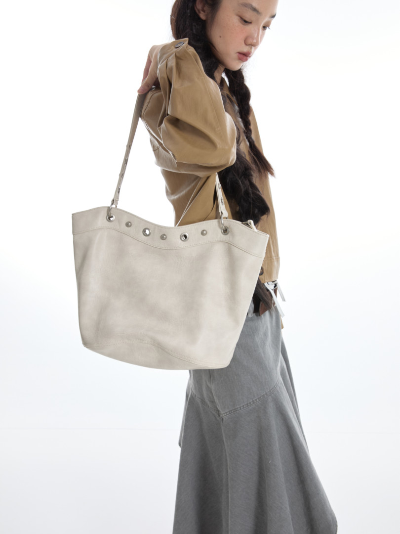 Woman holding a large light-colored tote bag on a white background