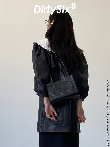 Model wearing a black outfit with a small black shoulder bag