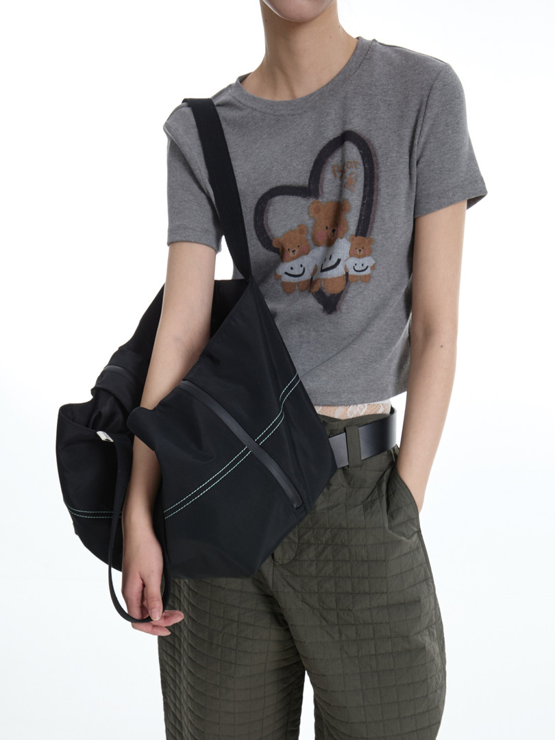 Gray graphic t-shirt worn by a model with a black shoulder bag