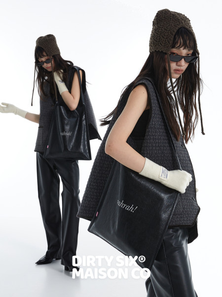 Fashion model wearing a black textured outfit with a black tote bag and knit hat