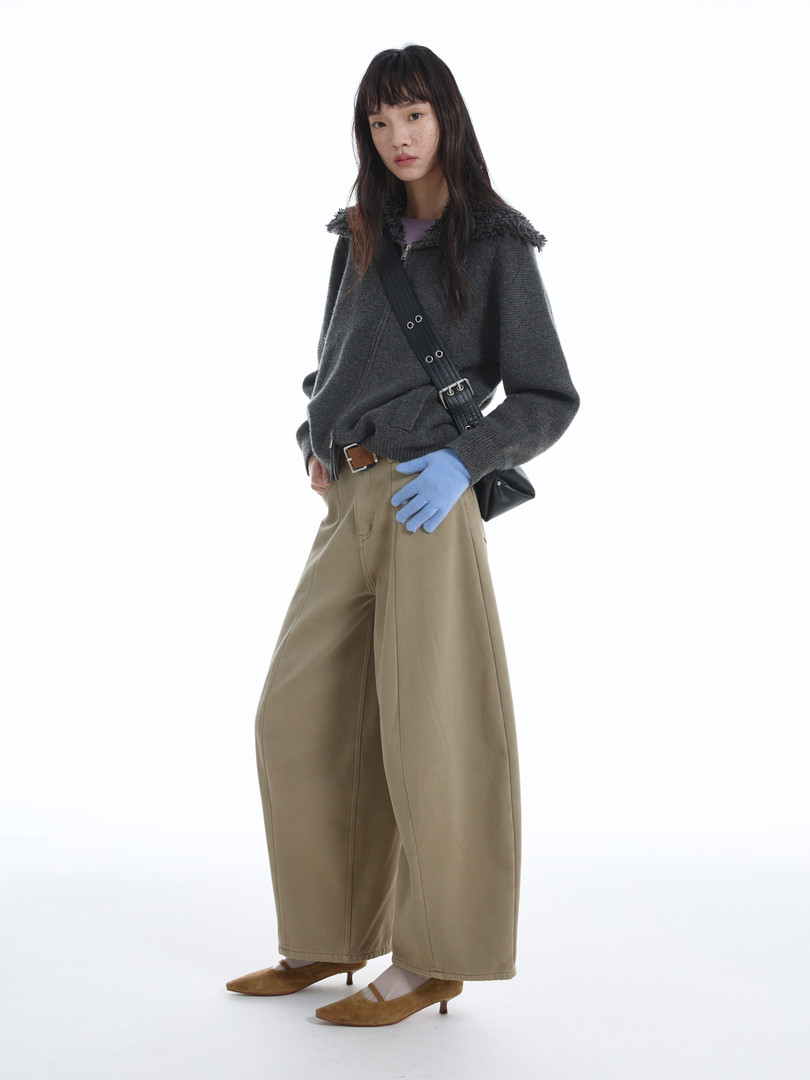 Model wearing a dark gray knit zip-up sweater with wide-leg beige pants and heeled flats