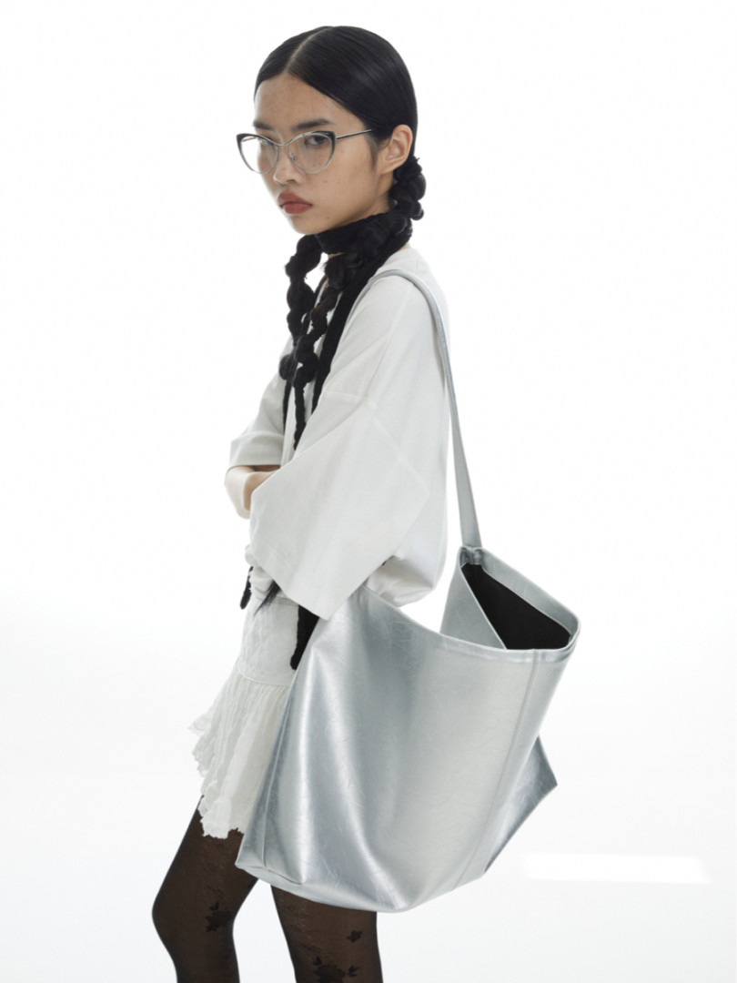 Silver tote bag worn by a model on a white background