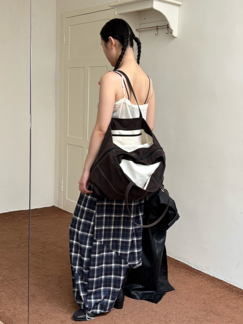Model wearing plaid wide-leg pants with a large black shoulder bag
