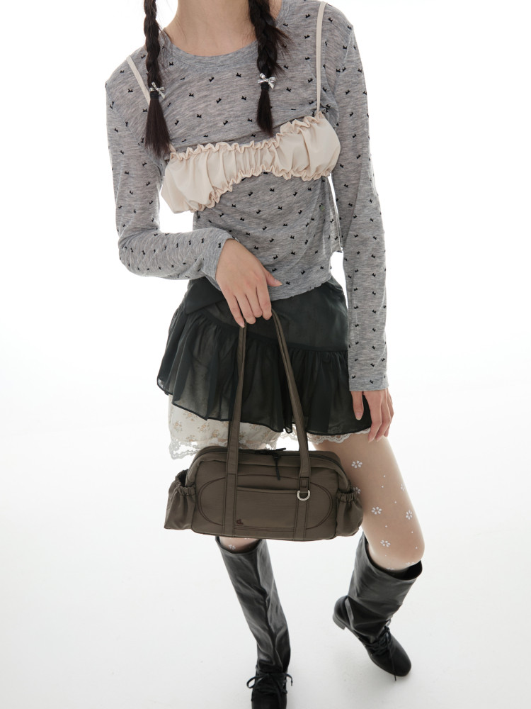 Fashion model wearing a layered grey top, black mini skirt, boots, and carrying a brown handbag