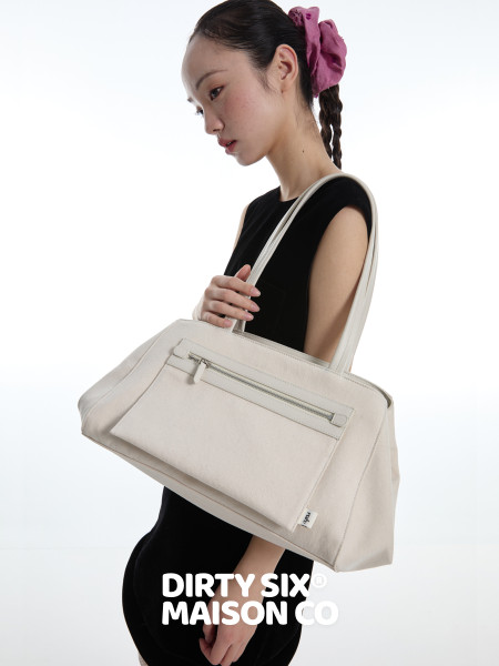 Cream oversized tote bag worn on a model against a white background
