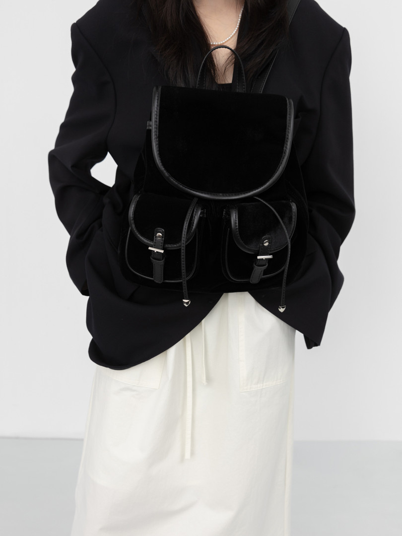 Black backpack worn by a model with front flap pockets