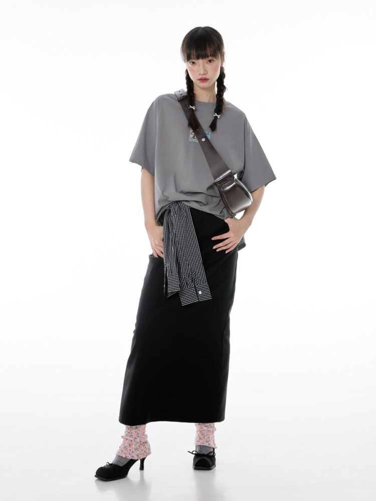 Model wearing a gray oversized T-shirt, black skirt, and crossbody bag