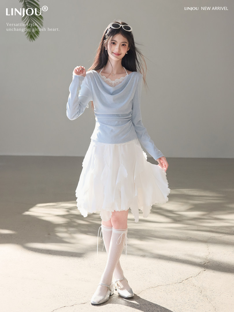 Model wearing a light blue long-sleeve top with a white layered skirt and white shoes