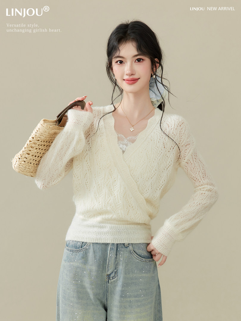 Model wearing a cream knit sweater with jeans and carrying a woven handbag