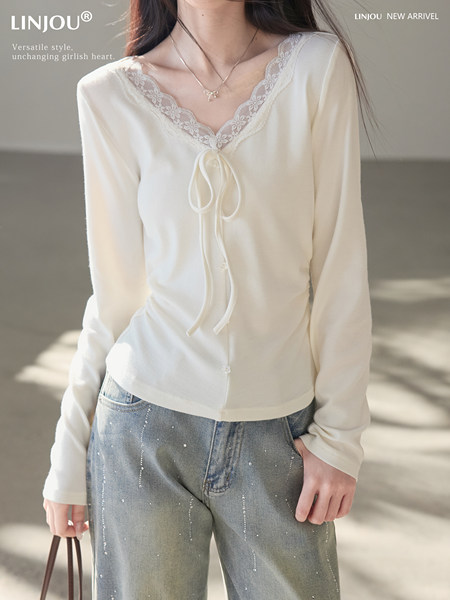 White long-sleeve lace-trim top worn with jeans on a model