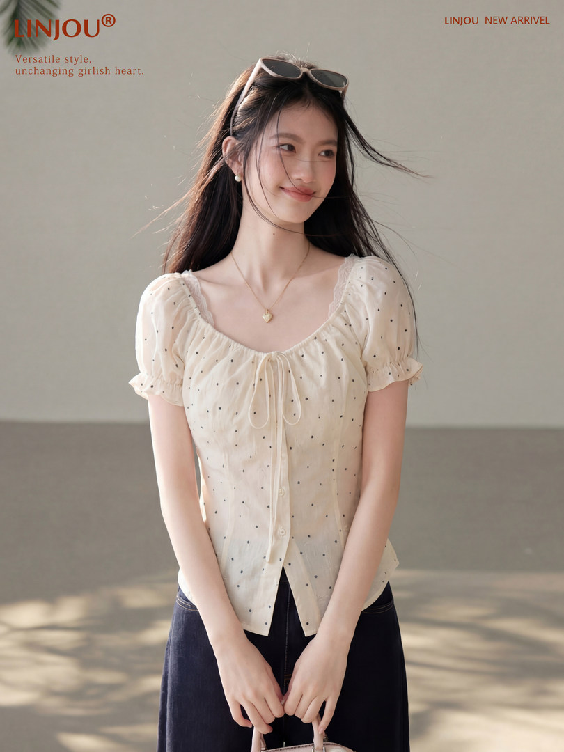Model wearing a cream polka dot short-sleeve blouse