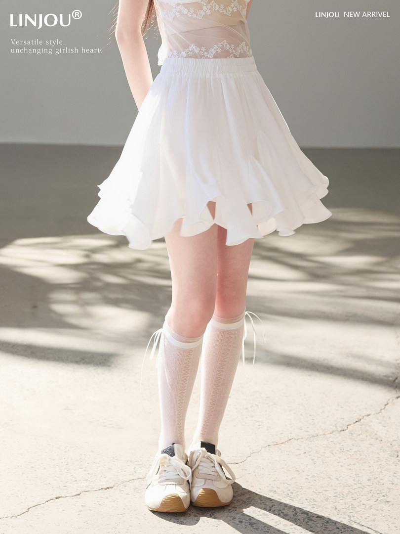 White flowy skirt worn by a model with lace top and sneakers