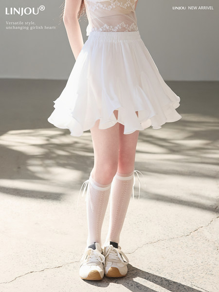 White flowy skirt worn by a model with lace top and sneakers