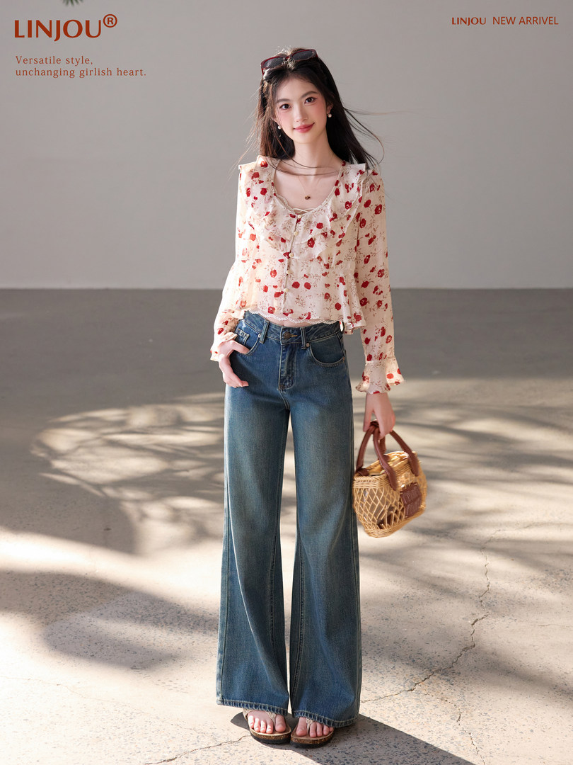 Model wearing a floral long-sleeve blouse with wide-leg jeans and a woven handbag