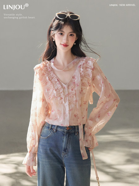 Model wearing a sheer floral ruffled blouse with jeans