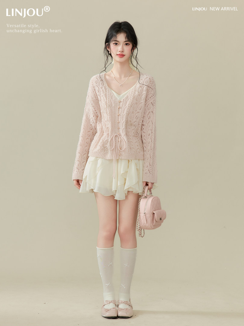 Model wearing a pale pink lace cardigan and cream mini skirt with pink accessories.