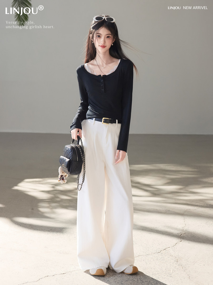 Model wearing a black long-sleeve top with white wide-leg pants and a small black backpack