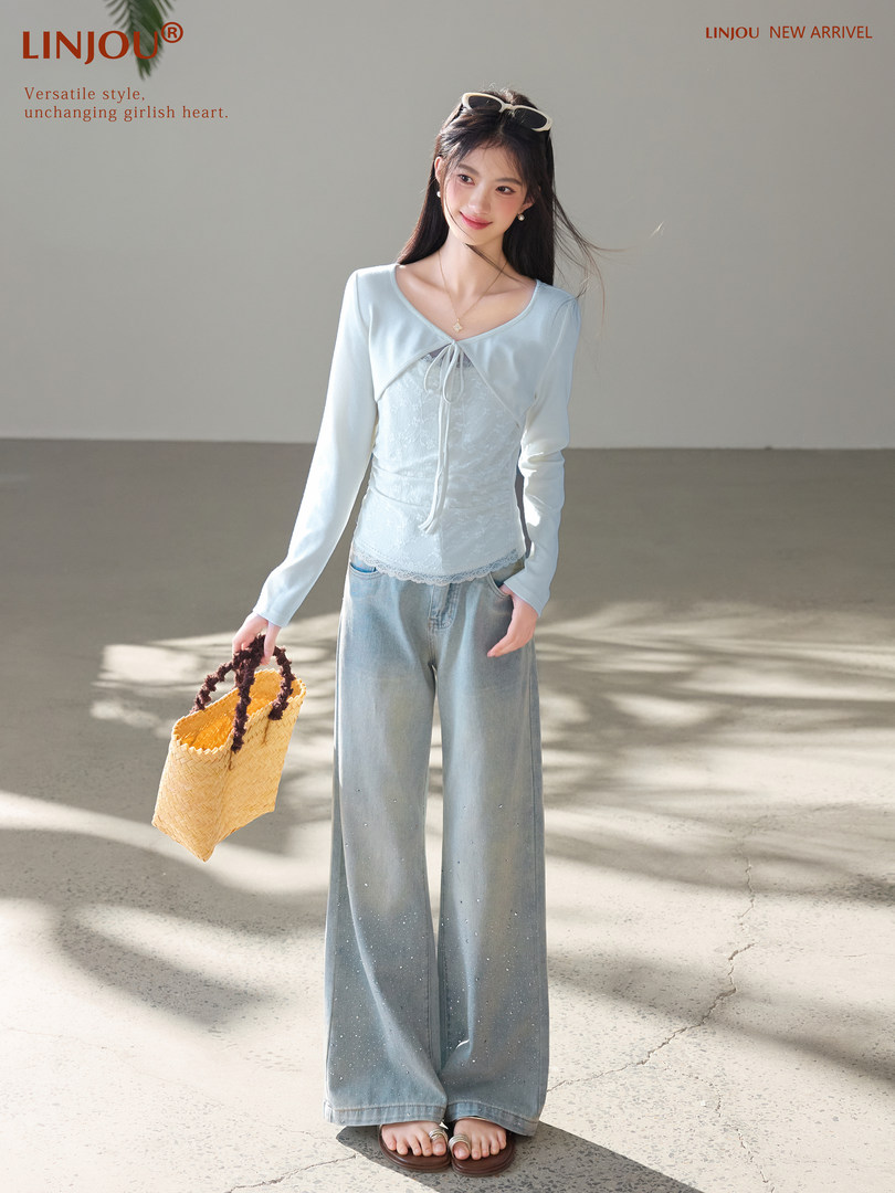 Model wearing a light blue long-sleeve top with wide-leg jeans and a woven tote bag