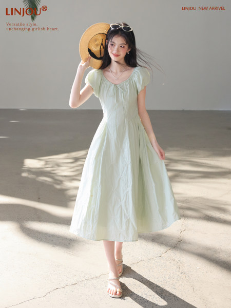 Model wearing a light green puff-sleeve midi dress with a flowing skirt