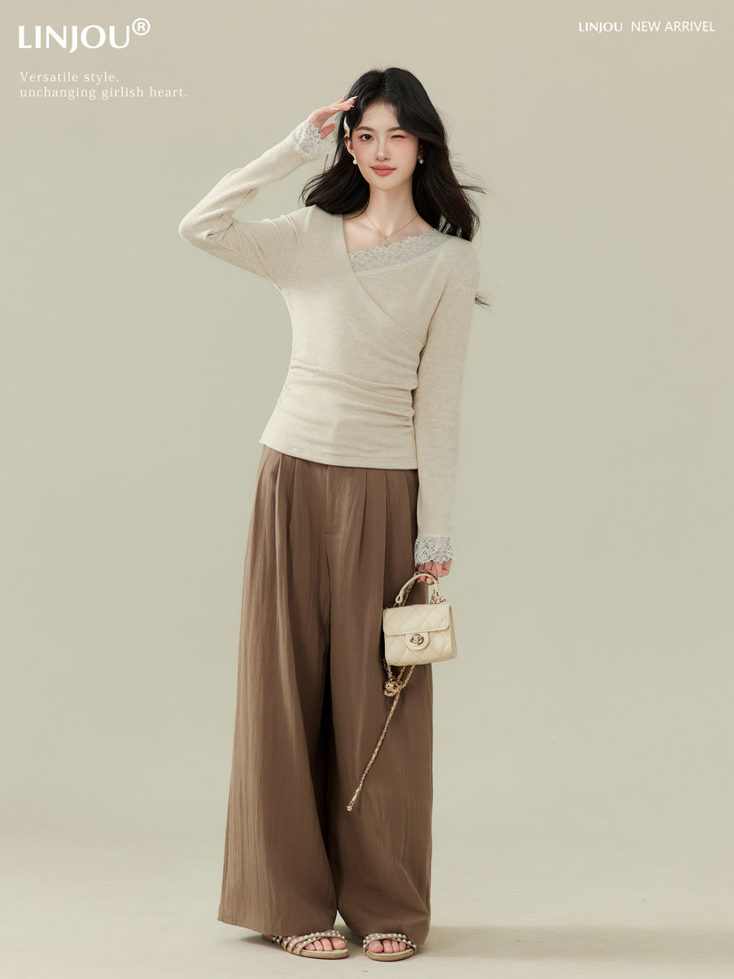 Model wearing a cream lace-trim long-sleeve top with brown wide-leg pants and a small handbag