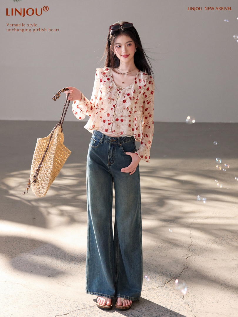 Model wearing a floral long-sleeve blouse with wide-leg blue jeans and a woven bag