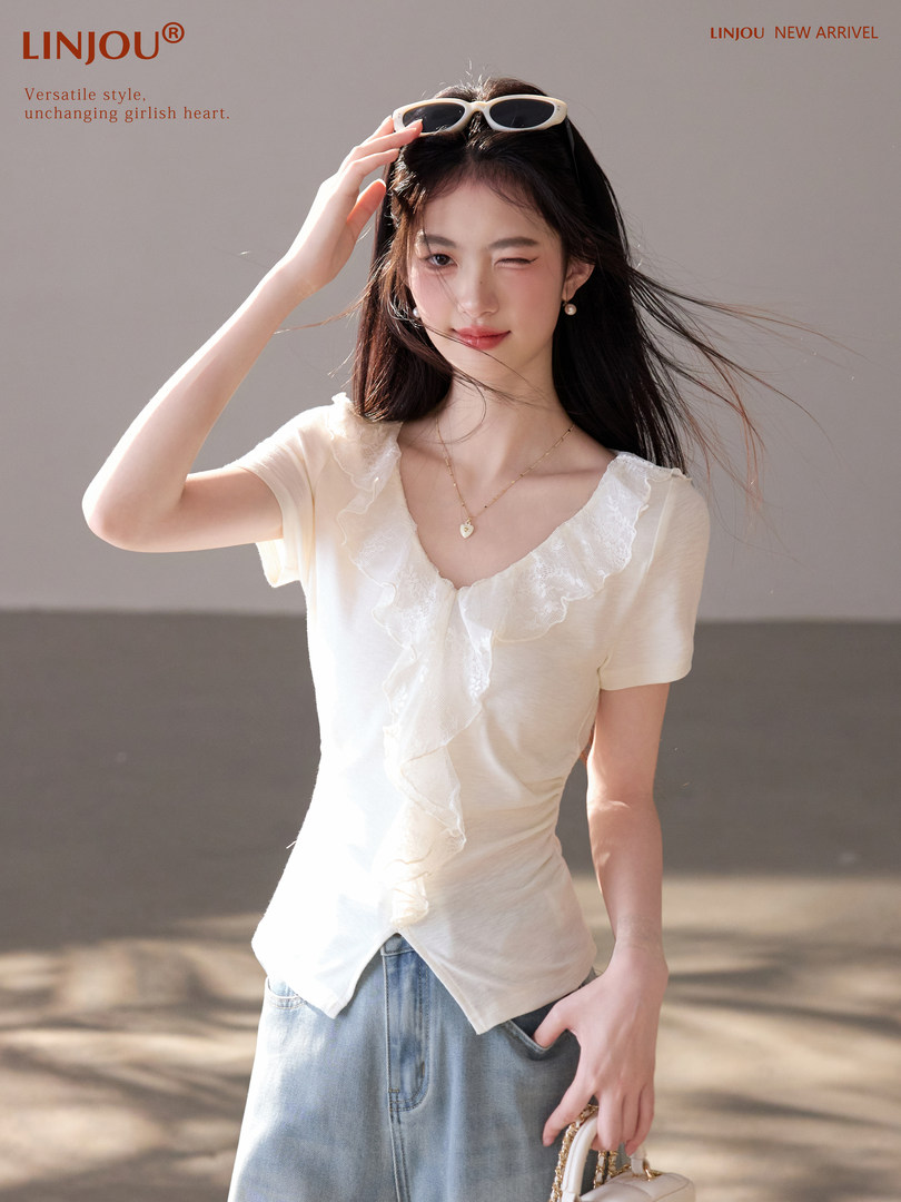 Model wearing a cream ruffled short-sleeve top with light blue jeans and a small handbag