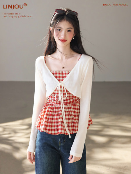 Model wearing a white tie-front cardigan over a red gingham top with jeans