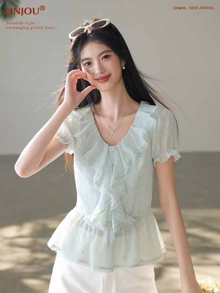 Model wearing a light blue ruffled short-sleeve blouse