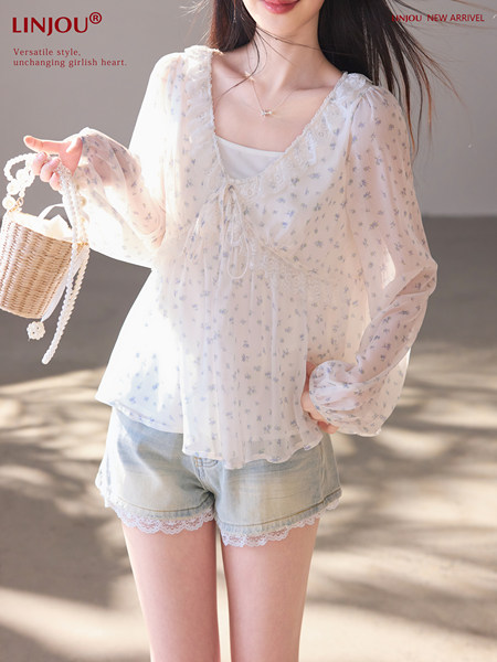 Model wearing a sheer floral lace-trim blouse with denim shorts
