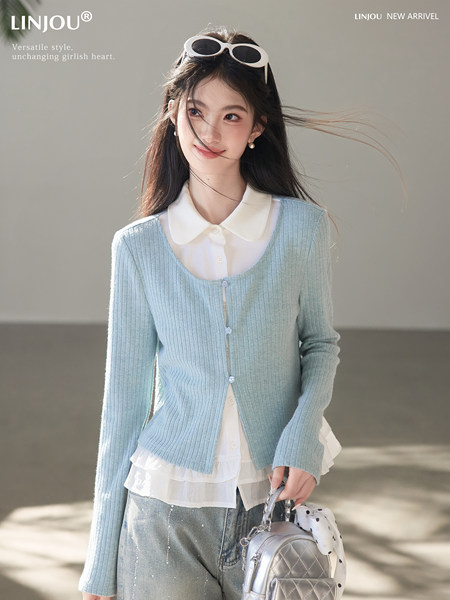 Model wearing a light blue ribbed cardigan over a white blouse with jeans and a small backpack