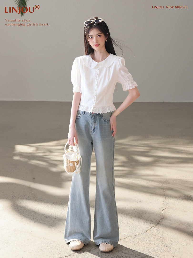 Model wearing a white puff-sleeve blouse with lace trim and light blue flared jeans