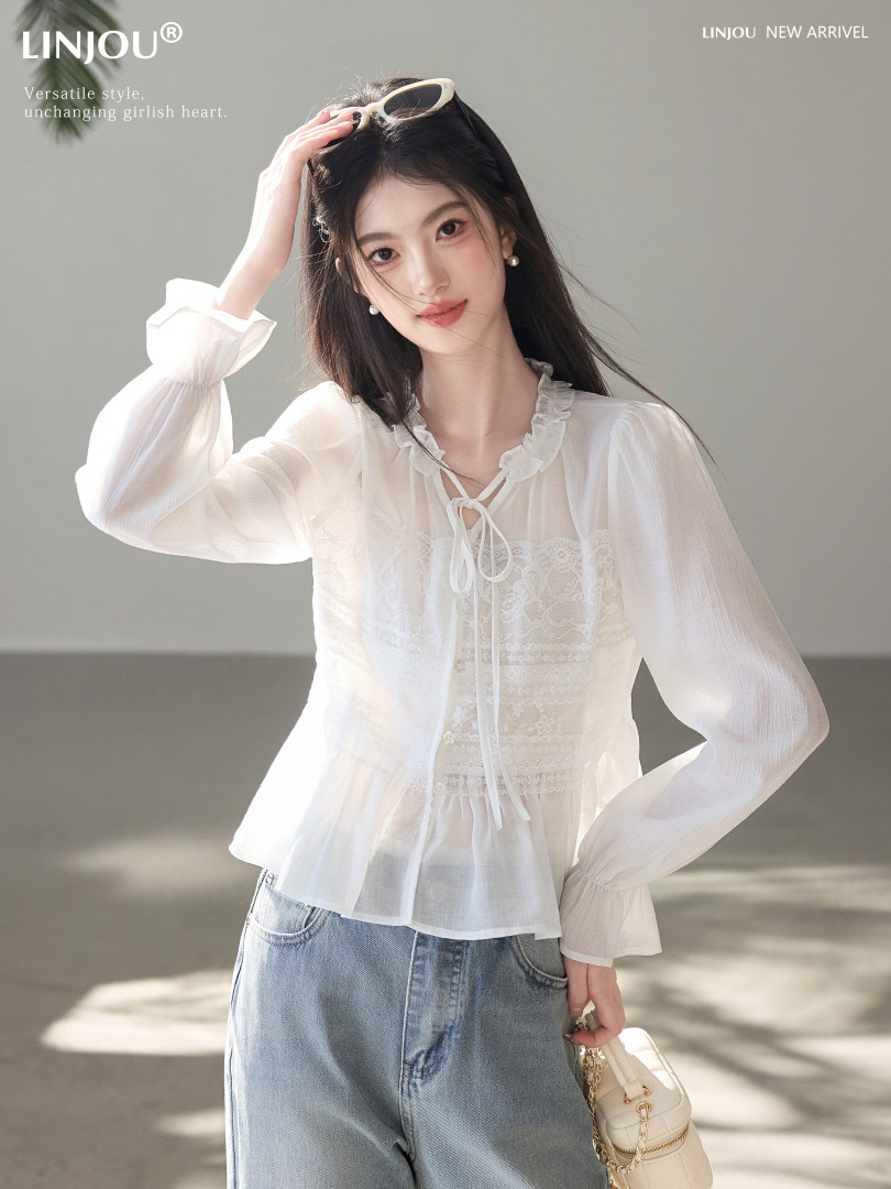Woman wearing a white sheer ruffled blouse with lace detail and blue jeans