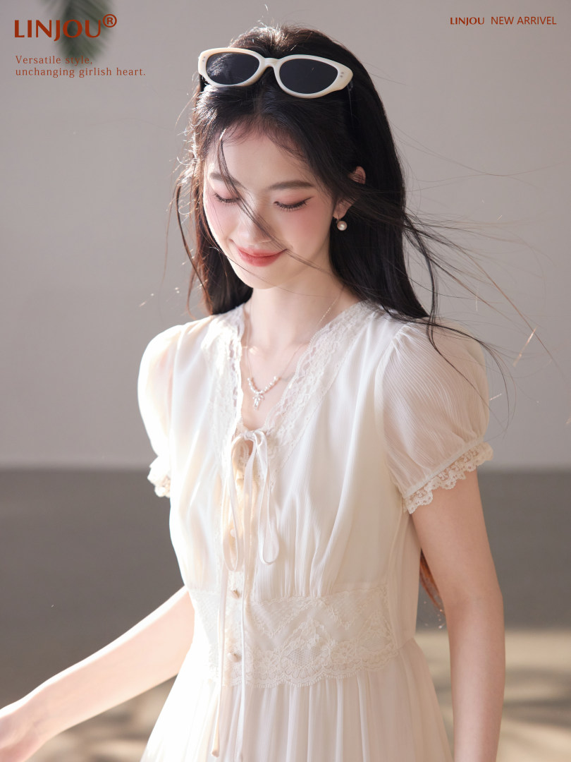 Woman wearing a white lace dress with short sleeves and a tied front detail