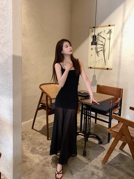 Woman wearing a black sleeveless maxi dress in a cafe