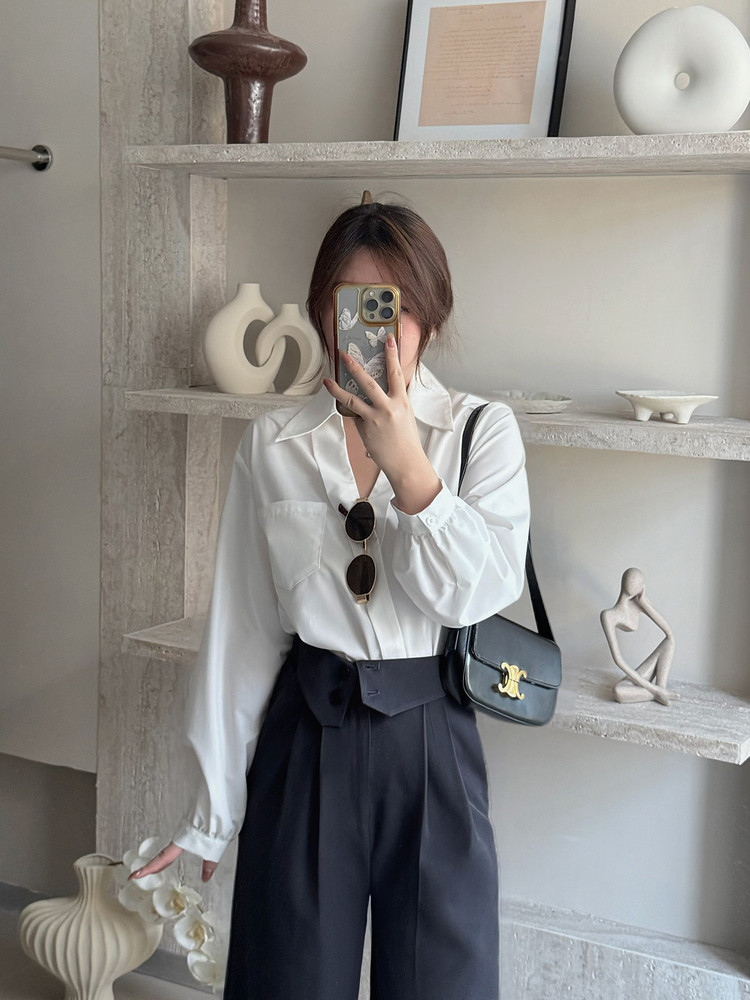 Woman wearing a white blouse with dark wide-leg pants and a black shoulder bag