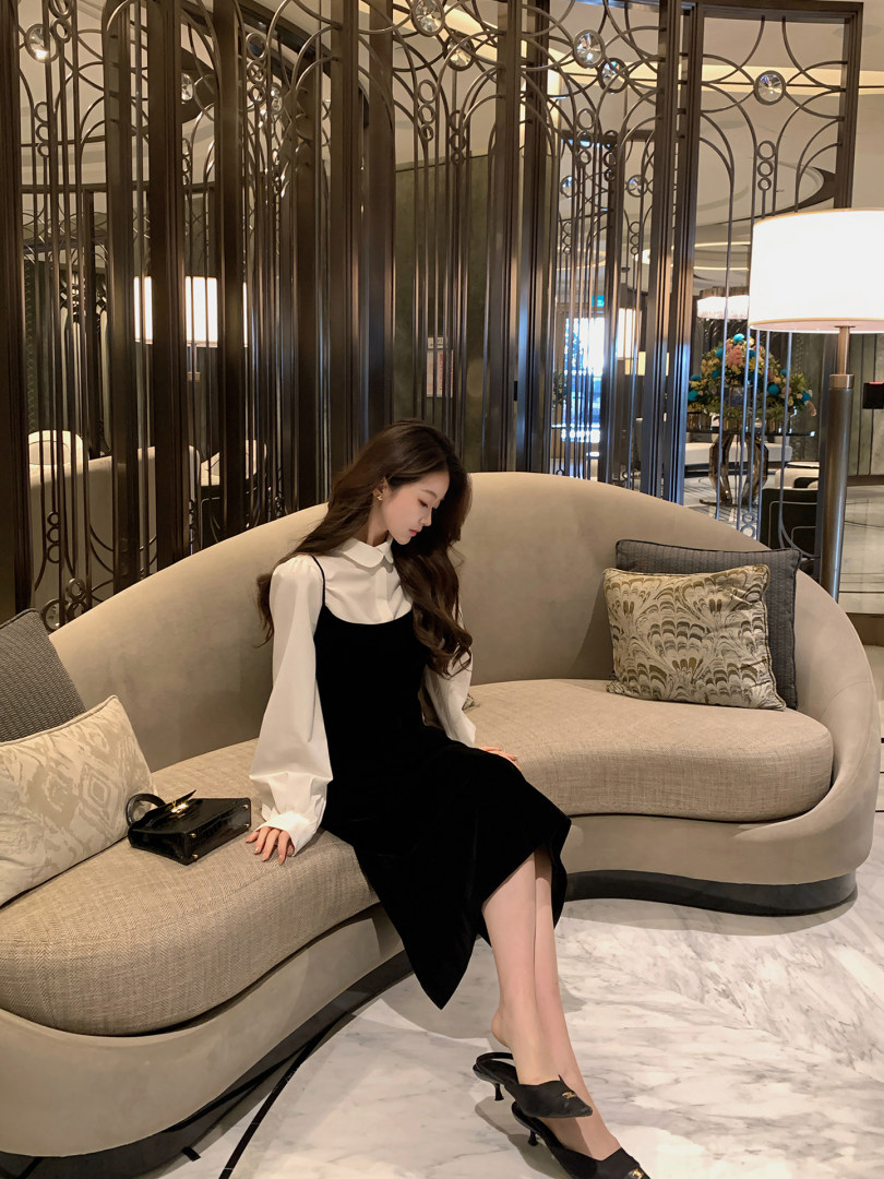 Woman wearing a black midi dress with a white blouse in a lounge setting