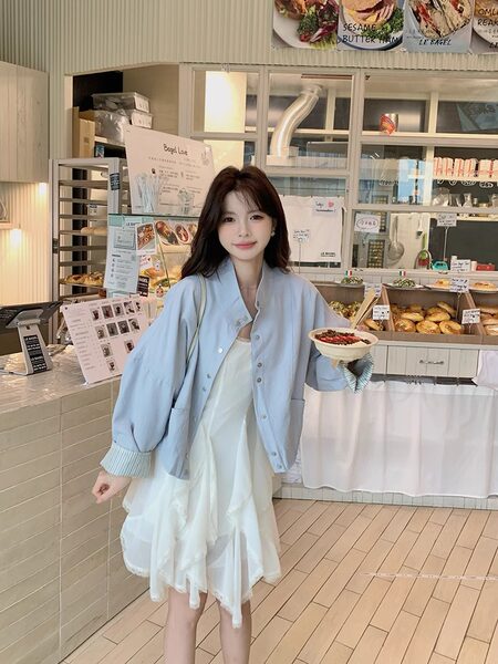 Woman wearing a light blue jacket over a white dress in a cafe