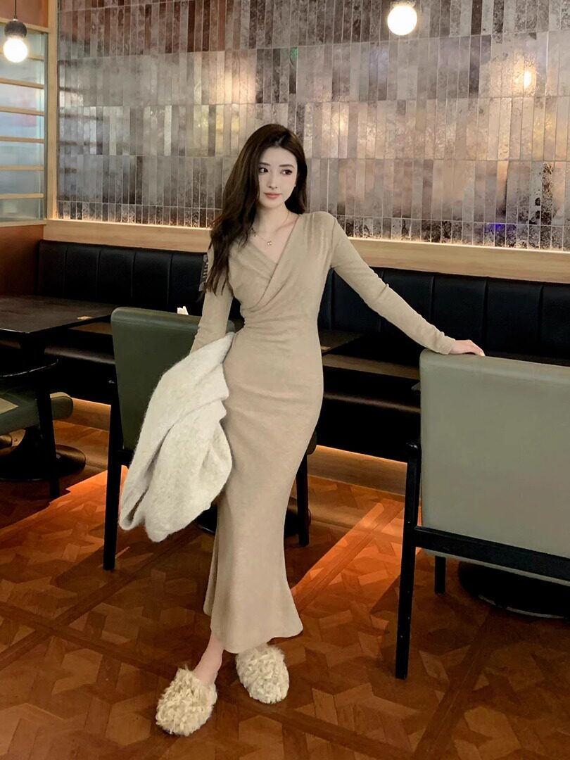 Beige long-sleeve fitted maxi dress worn by a woman indoors