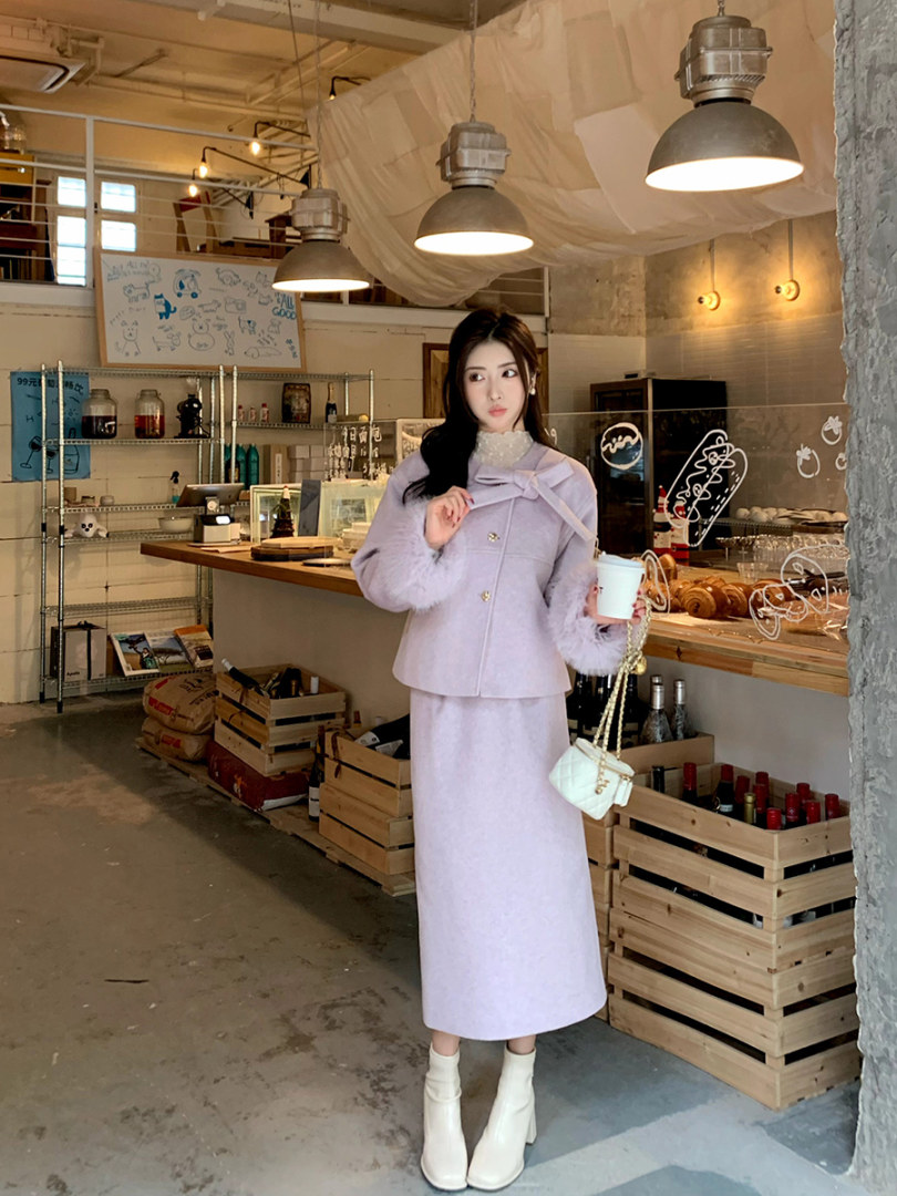 Woman wearing a light lavender coordinated jacket and long skirt outfit with white ankle boots