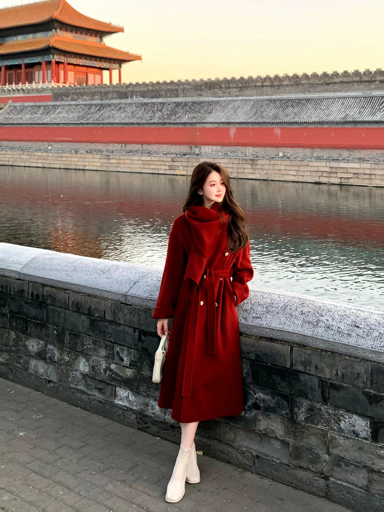 Woman wearing a long red belted coat with white ankle boots