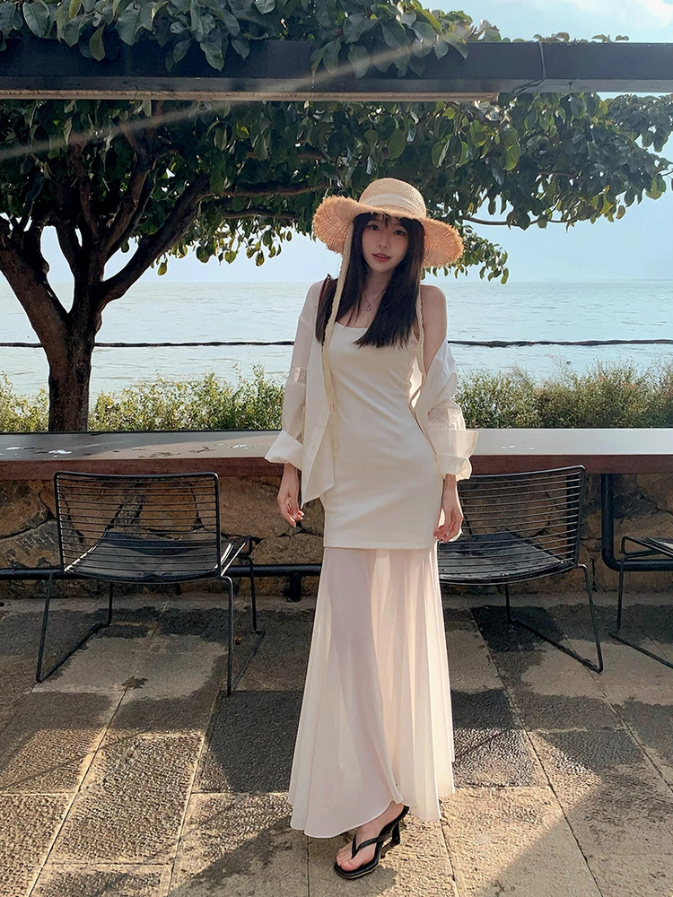 Woman wearing a cream maxi dress and light cardigan by the seaside