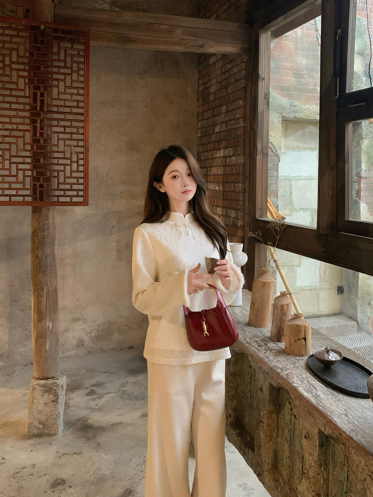 Woman modeling a cream-colored long-sleeve outfit with a burgundy handbag