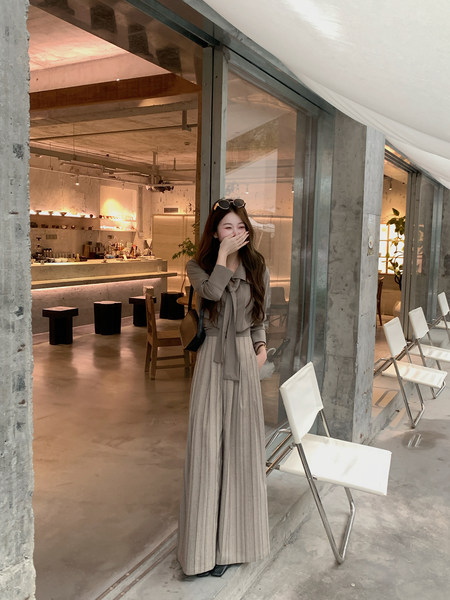 Woman wearing a taupe blouse and striped wide-leg pants in a café
