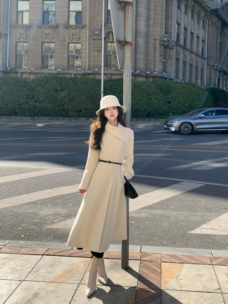 Woman wearing a cream long coat and matching hat on a city street