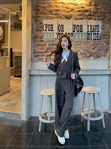 Model wearing a dark gray tailored suit with light blue accents and white sneakers