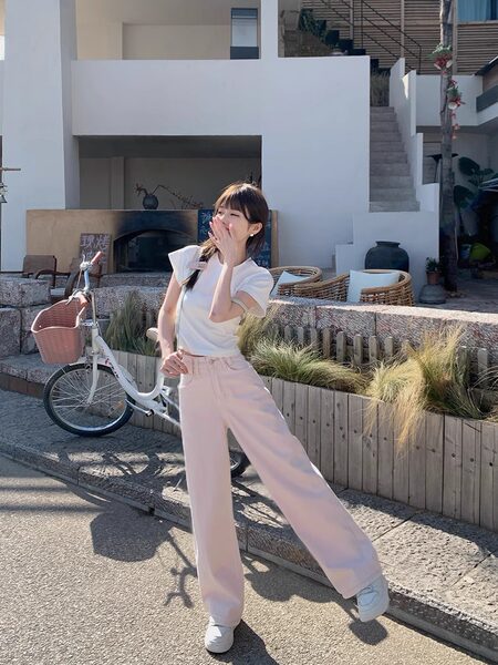 Woman wearing a white top and light pink wide-leg pants outdoors