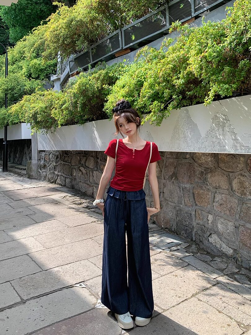 Woman wearing a red short-sleeve top with dark wide-leg pants outdoors